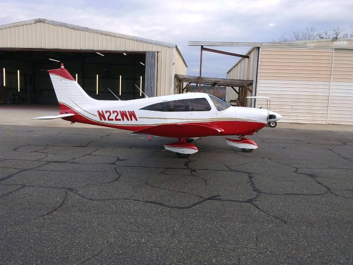 Piper Cherokee in red and white parked outside the hangars