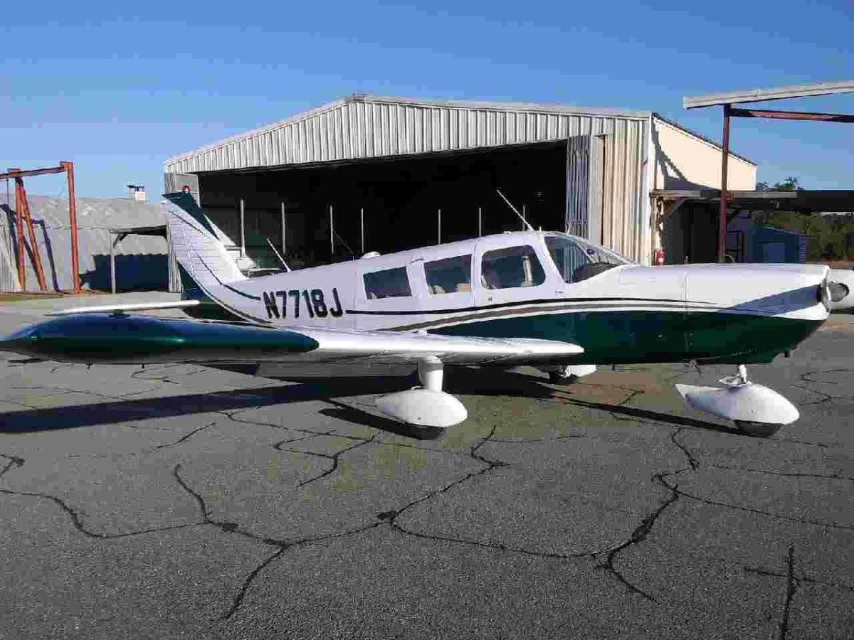 Piper on the ramp in a red and white scheme under a clear sky