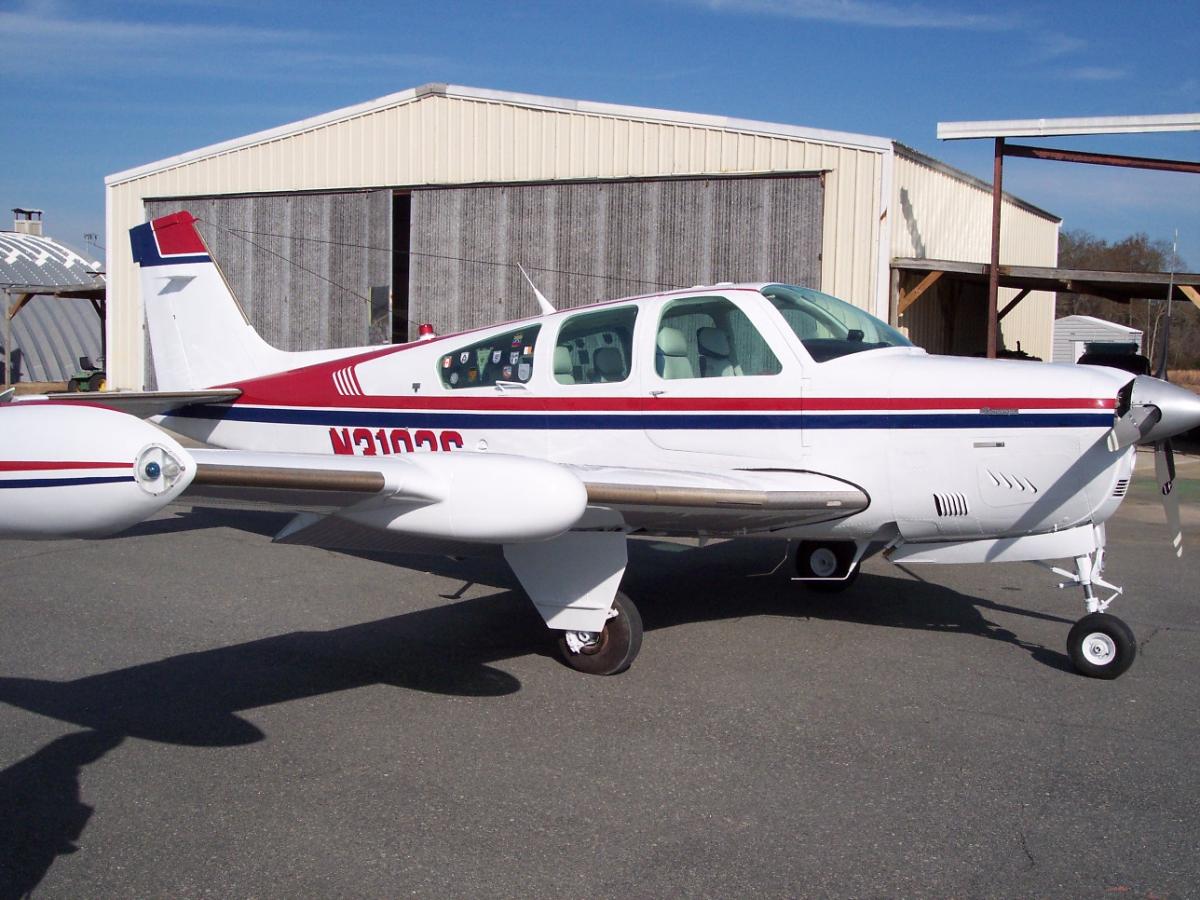 Cessna twin in white with a maroon belly stripe, front three-quarter view